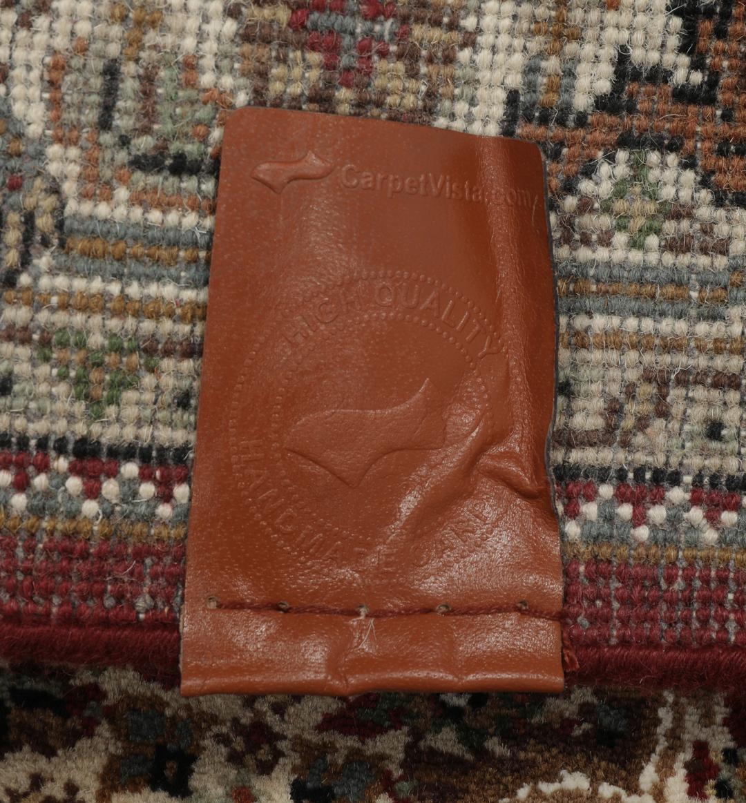 Een handgeknoopt Tabriz-tapijt uit India met een centraal medaillon in dieprood en crème.