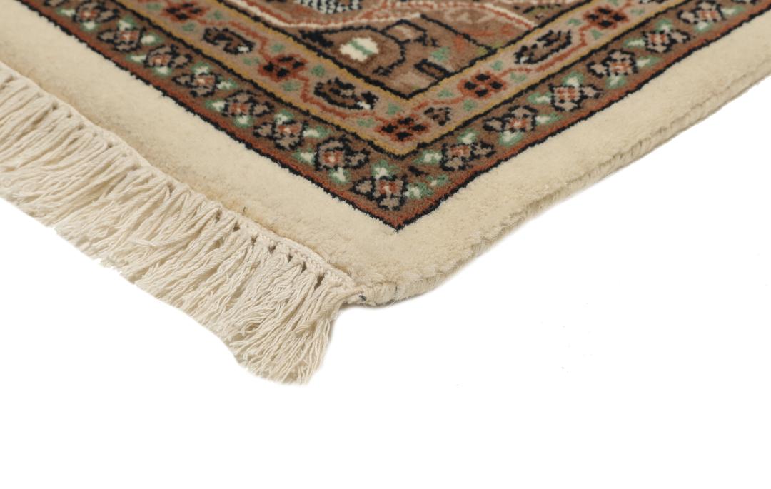 Een handgeknoopt Mir Indo-tapijt uit India met een beige veld en aardse bruine randen.
