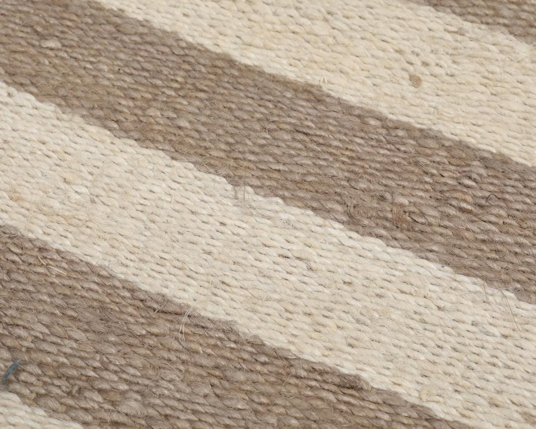 Beige og sort stribet tæppe lavet af jute.