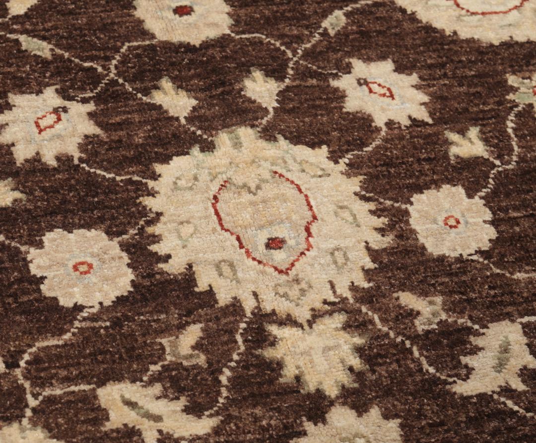 Un tapis Ziegler rectangulaire d'Afghanistan avec un champ marron foncé et des motifs floraux beiges.
