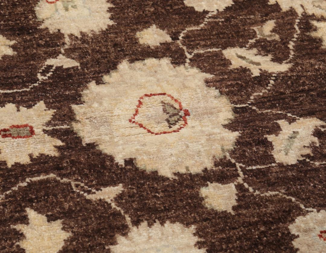 Un tapis Ziegler rectangulaire d'Afghanistan avec un champ marron foncé et des motifs floraux beiges.