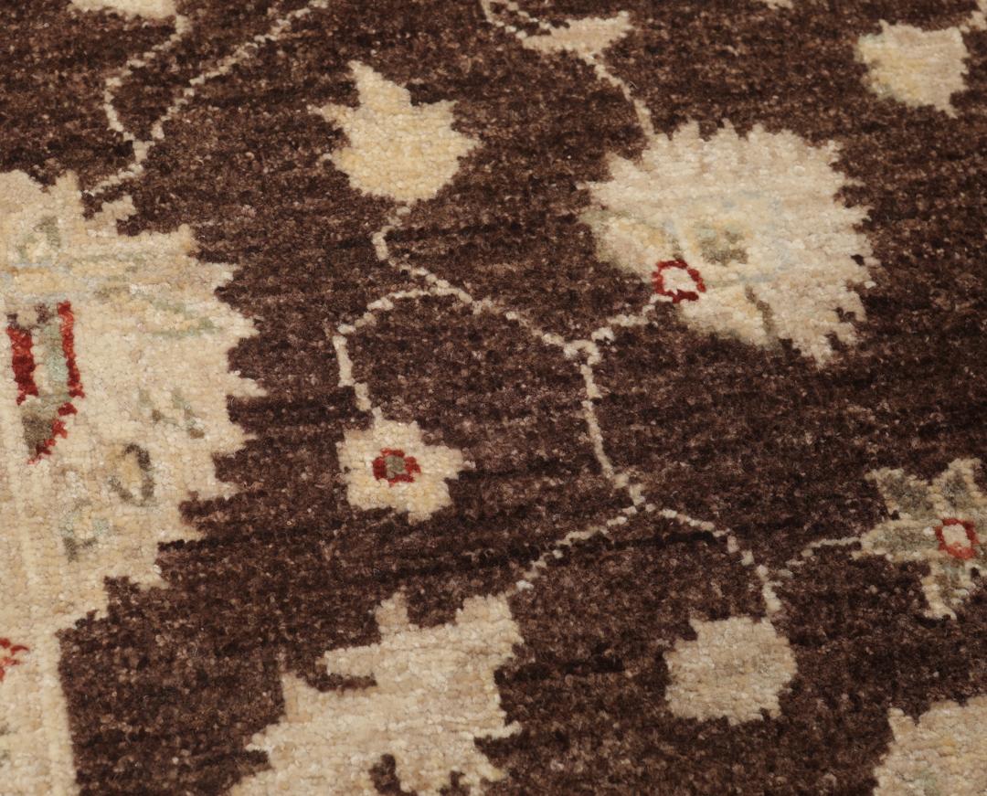 Un tapis Ziegler rectangulaire d'Afghanistan avec un champ marron foncé et des motifs floraux beiges.
