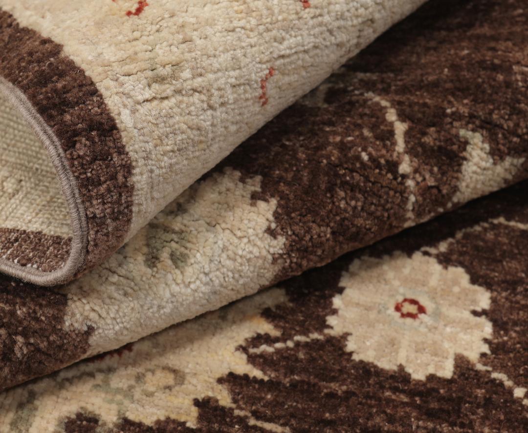 Un tapis Ziegler rectangulaire d'Afghanistan avec un champ marron foncé et des motifs floraux beiges.