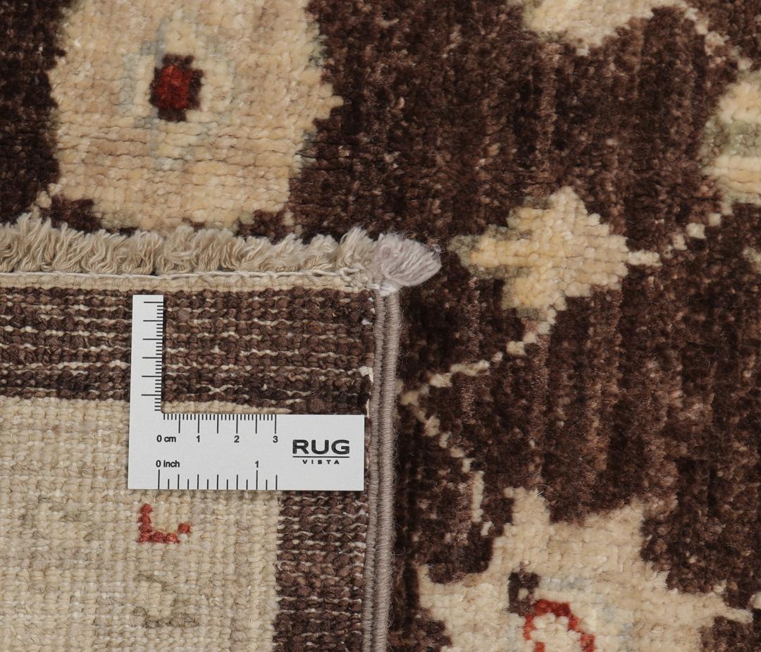 Un tapis Ziegler rectangulaire d'Afghanistan avec un champ marron foncé et des motifs floraux beiges.