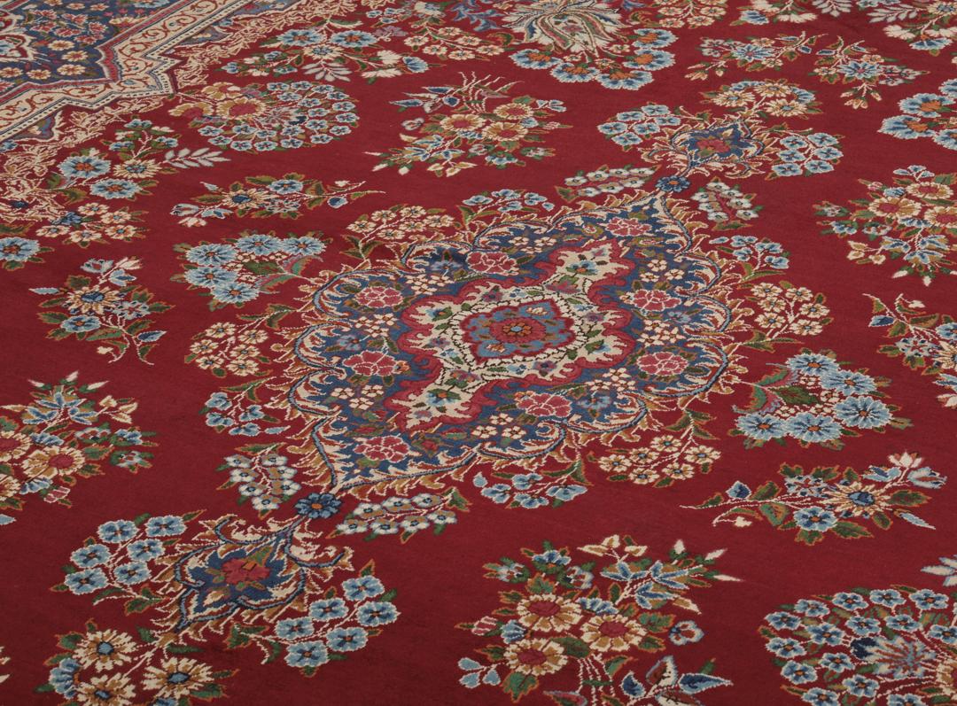 Een groot, handgeknoopt Yazd-tapijt uit het Midden-Oosten met een donkerrood veld en bloemmotieven.