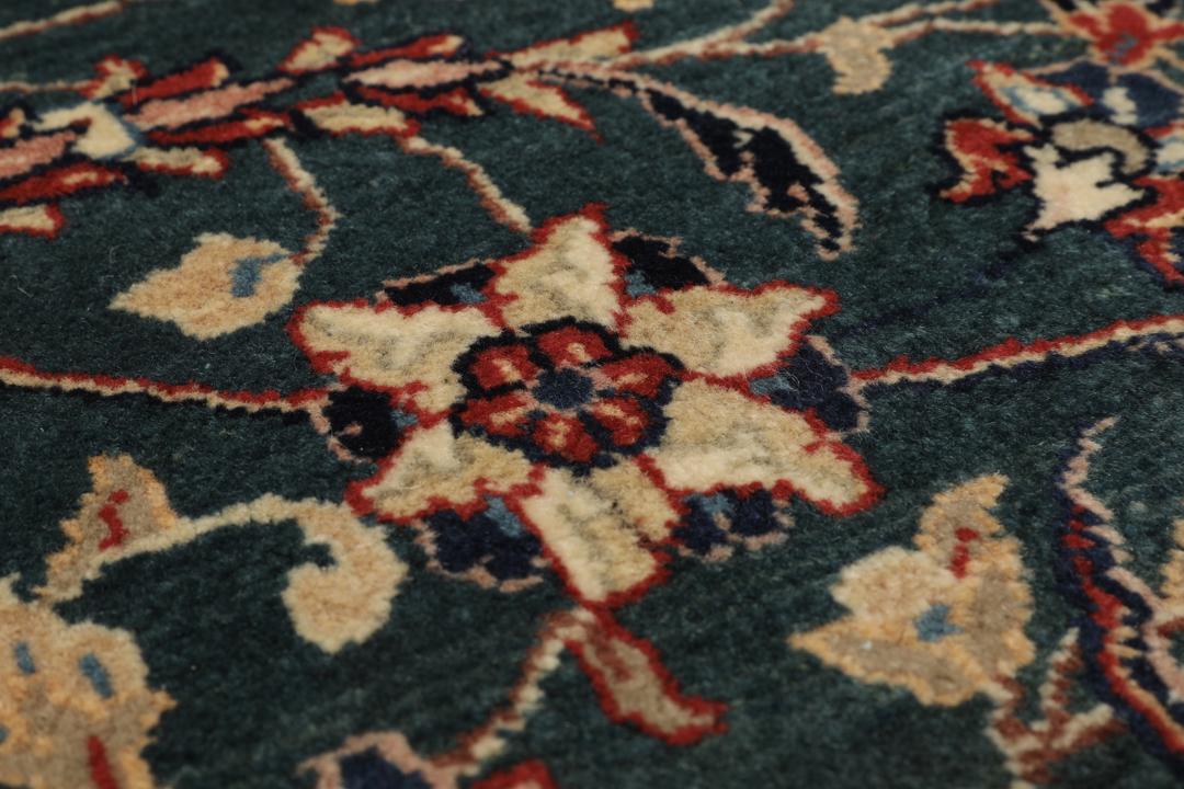 A hand-knotted Middle Eastern Sarough rug with a dark-blue field and floral patterns.