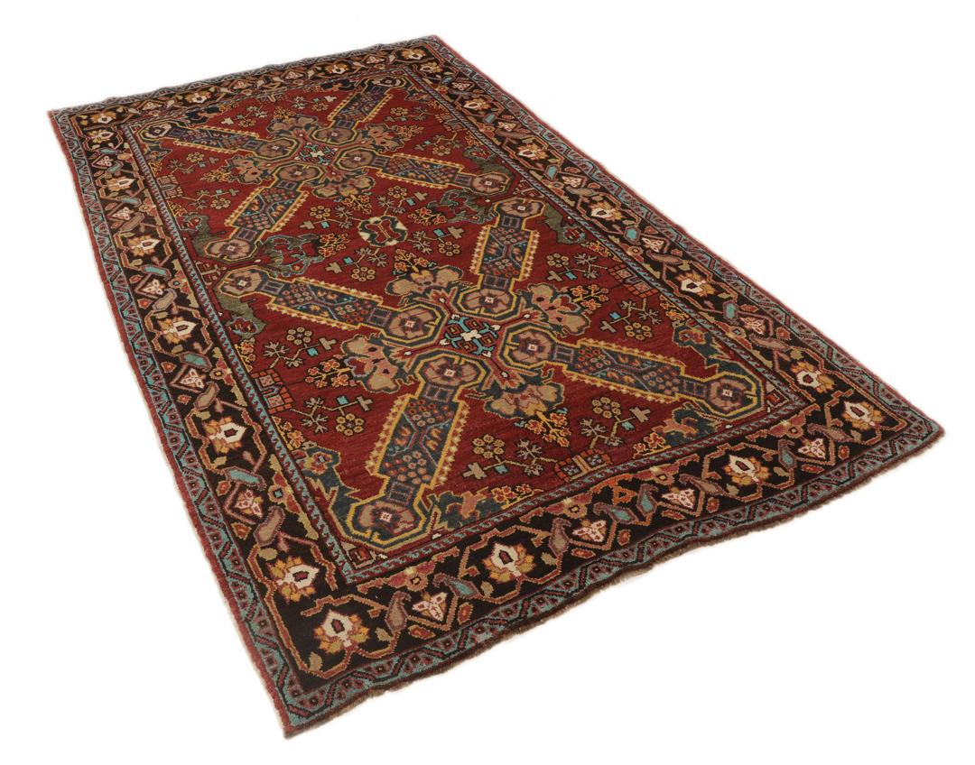 Antikt Shirvan-tæppe fra Mellemøsten med et levende rødt felt og komplekse geometriske motiver.