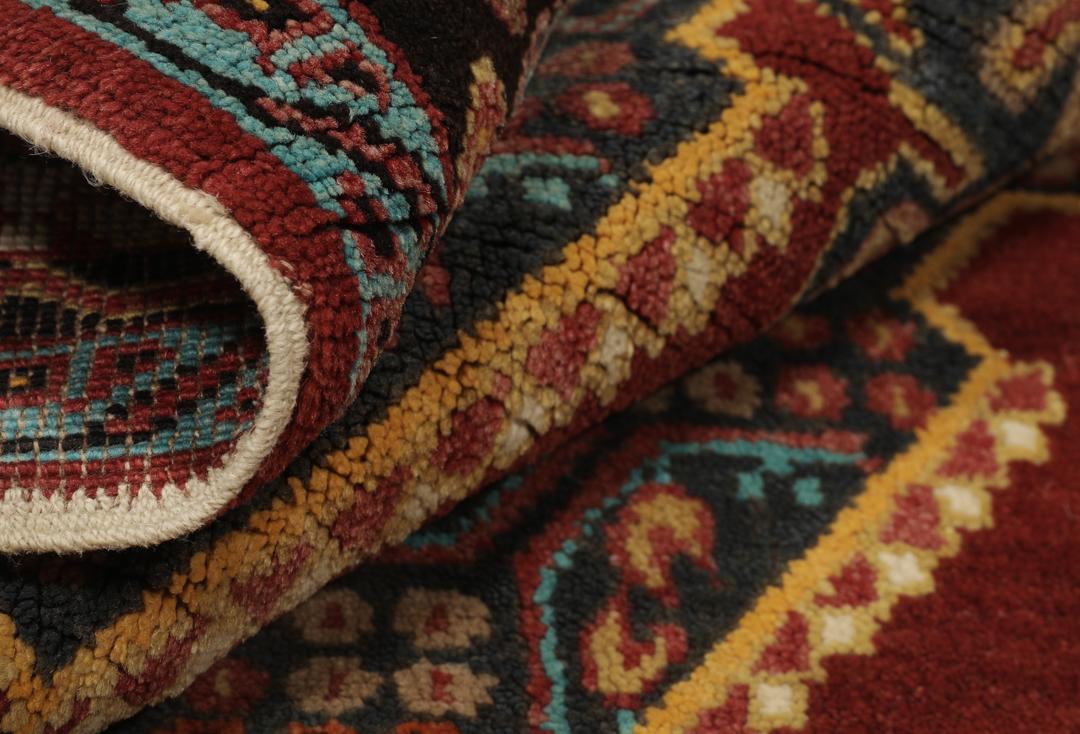 Antikt Shirvan-tæppe fra Mellemøsten med et levende rødt felt og komplekse geometriske motiver.
