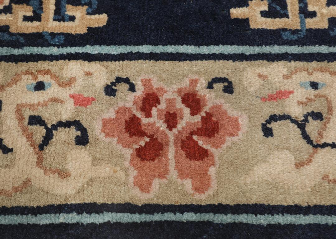 Antik kinesisk løber med blomstermotiver på en mørkeblå baggrund