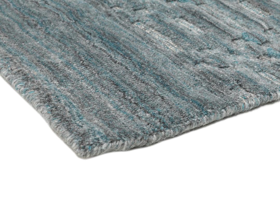 Un tapis rectangulaire bleu sarcelle avec un motif mosaïque texturé.