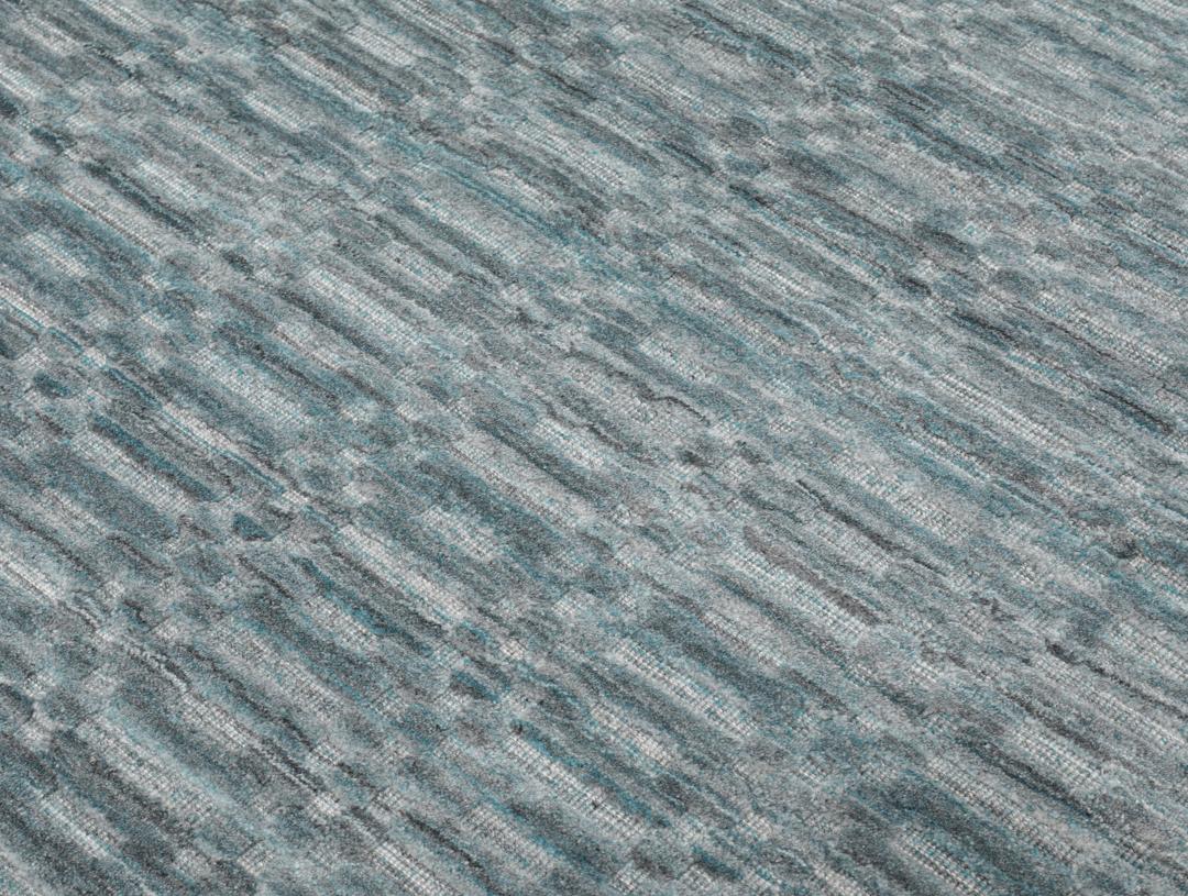 Un tapis rectangulaire bleu sarcelle avec un motif mosaïque texturé.