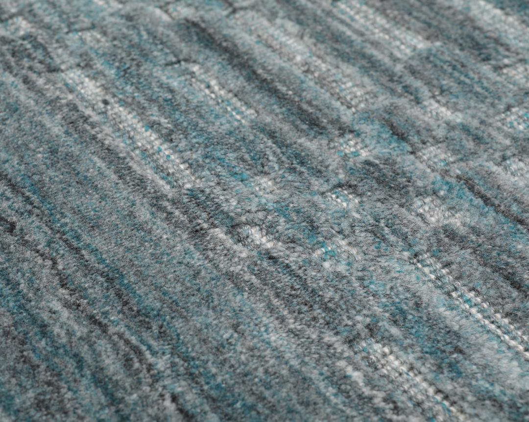 Un tapis rectangulaire bleu sarcelle avec un motif mosaïque texturé.