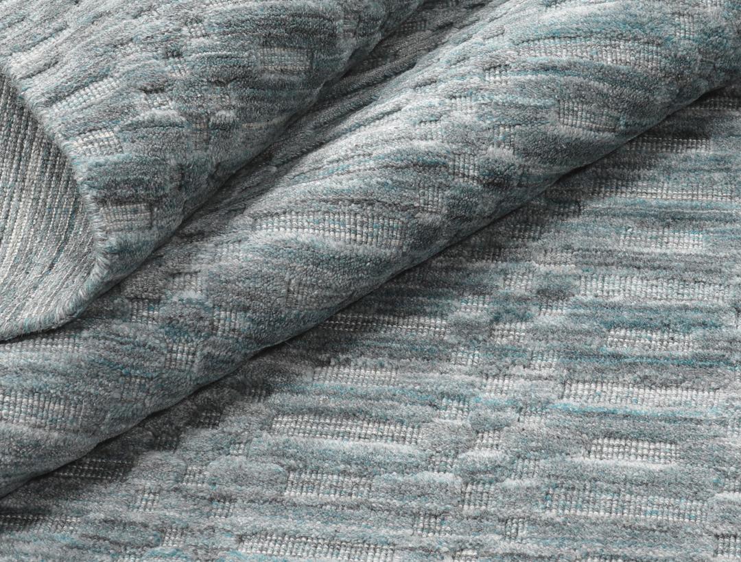 Un tapis rectangulaire bleu sarcelle avec un motif mosaïque texturé.