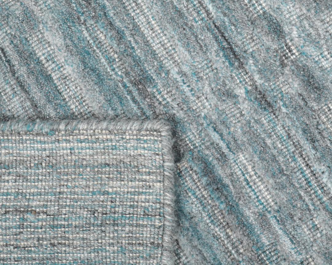 Un tapis rectangulaire bleu sarcelle avec un motif mosaïque texturé.