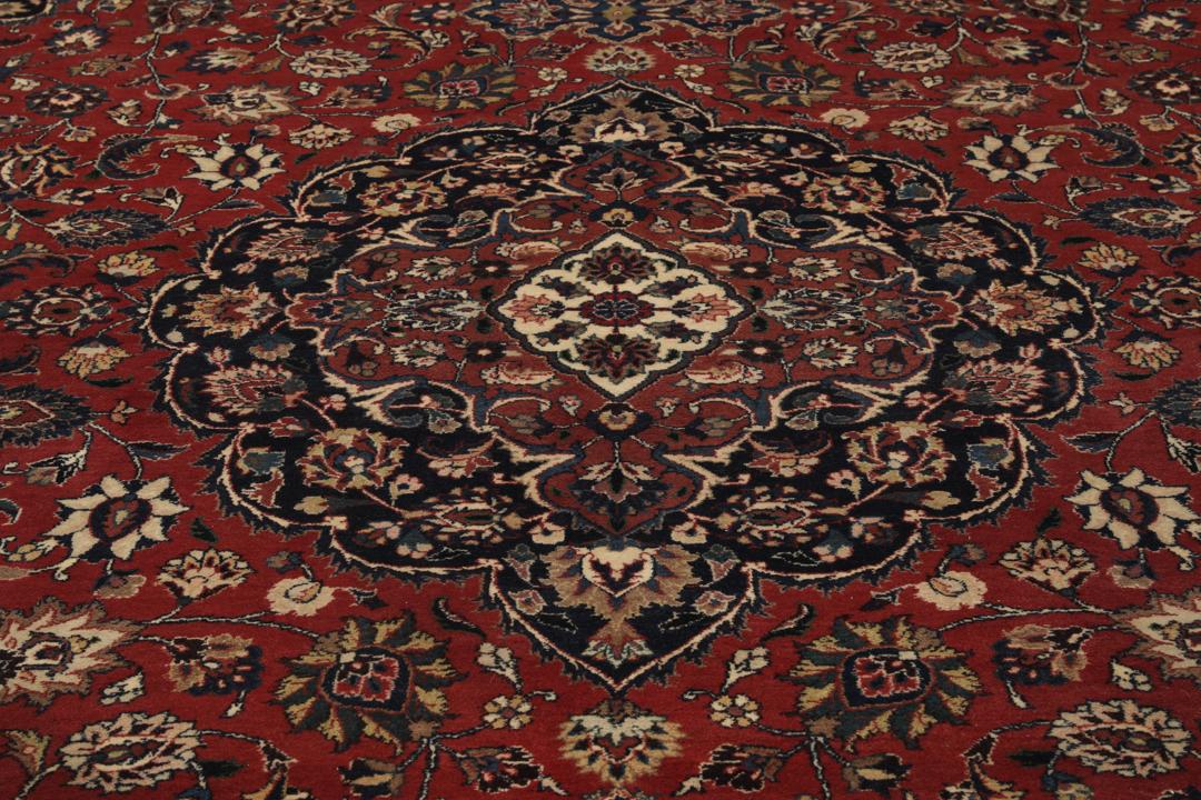 A large hand-knotted Mashad rug from the Middle East in deep red and blue tones