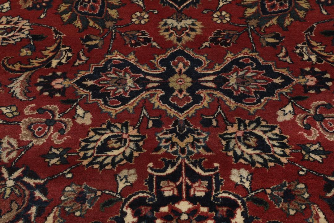 A large hand-knotted Mashad rug from the Middle East in deep red and blue tones
