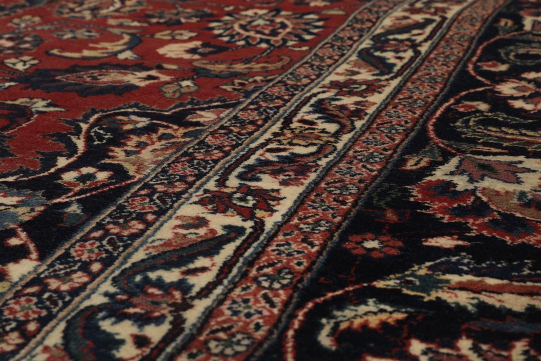A large hand-knotted Mashad rug from the Middle East in deep red and blue tones
