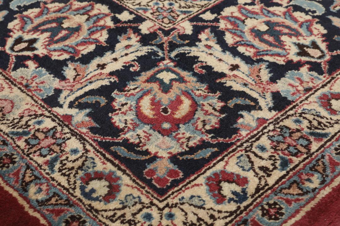 Hand-knotted Mashad rug from the Middle East in deep red and dark blue tones.