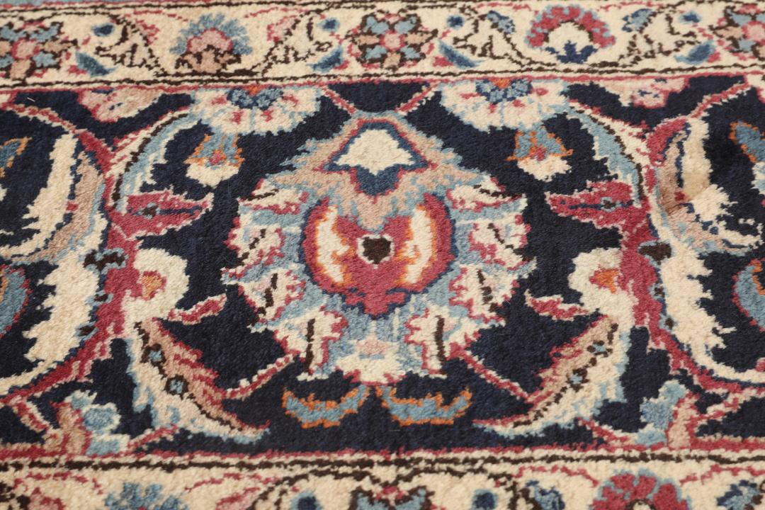 Hand-knotted Mashad rug from the Middle East in deep red and dark blue tones.