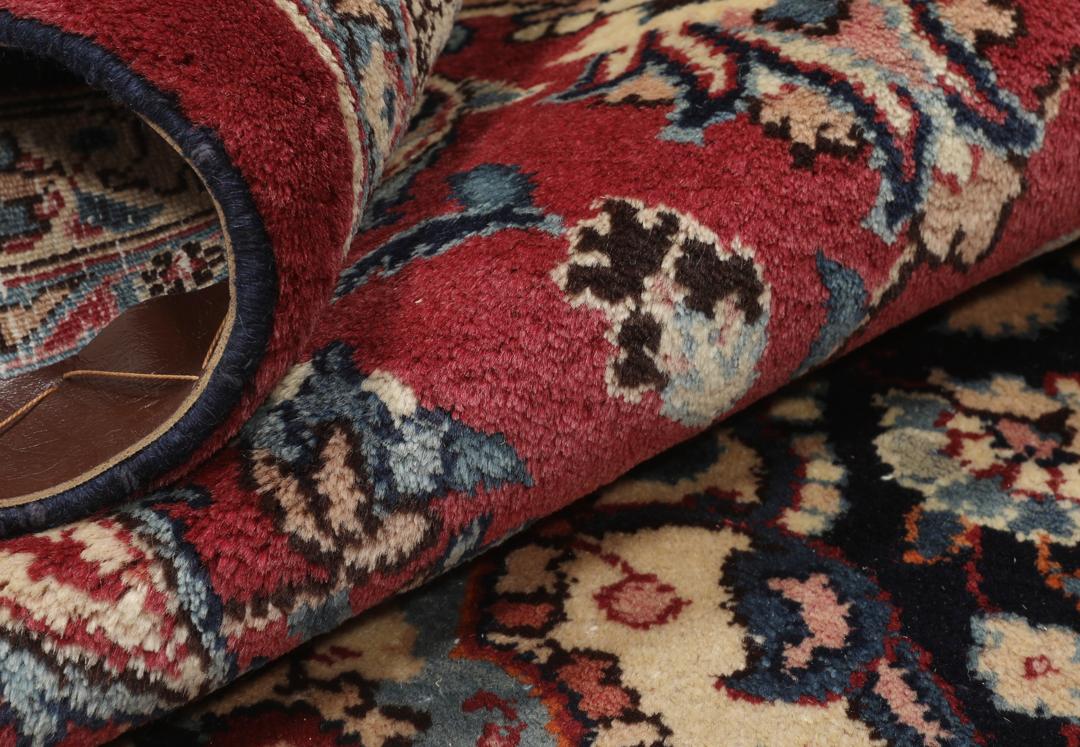 Hand-knotted Mashad rug from the Middle East in deep red and dark blue tones.