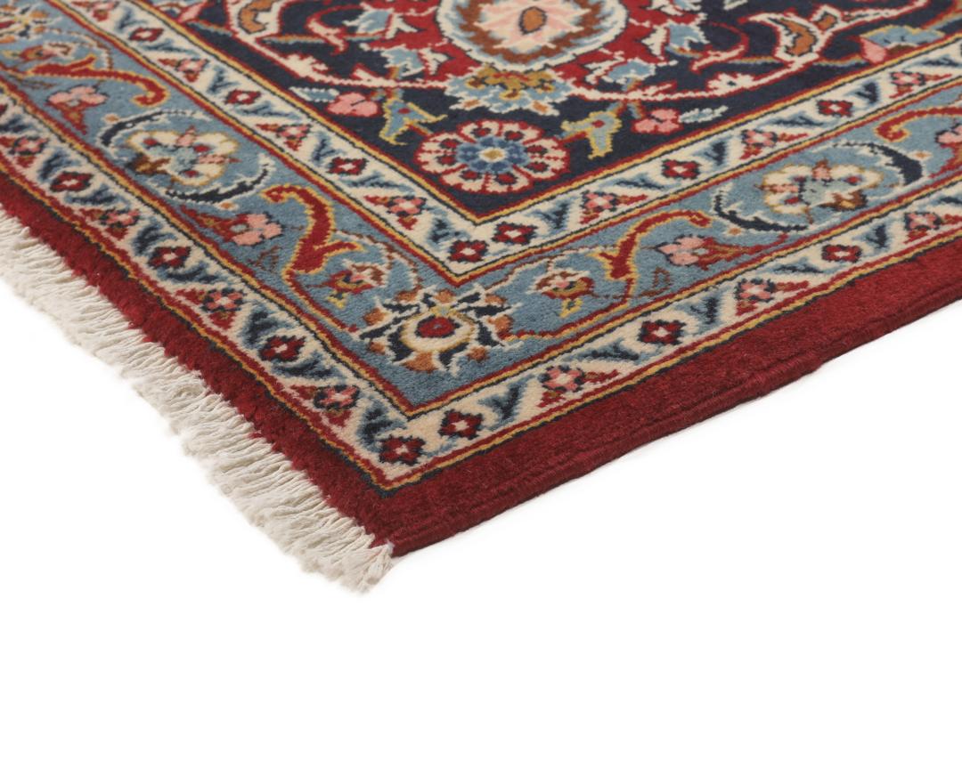 A hand-knotted Keshan rug from the Middle East with a red field and intricate floral patterns.