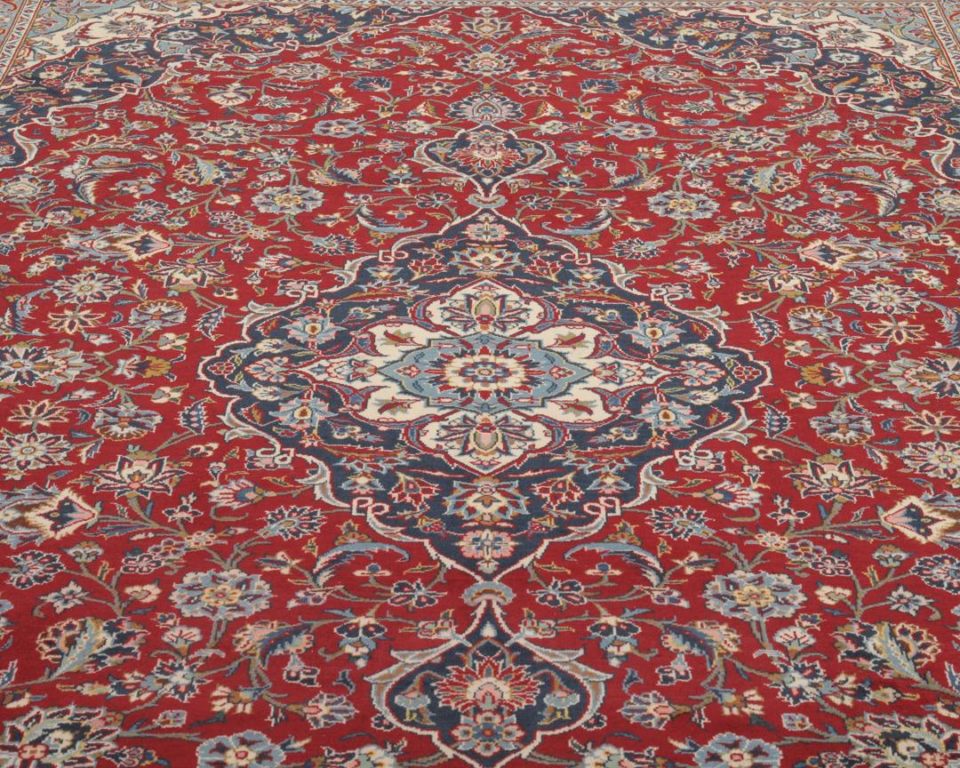 A hand-knotted Keshan rug from the Middle East with a red field and intricate floral patterns.