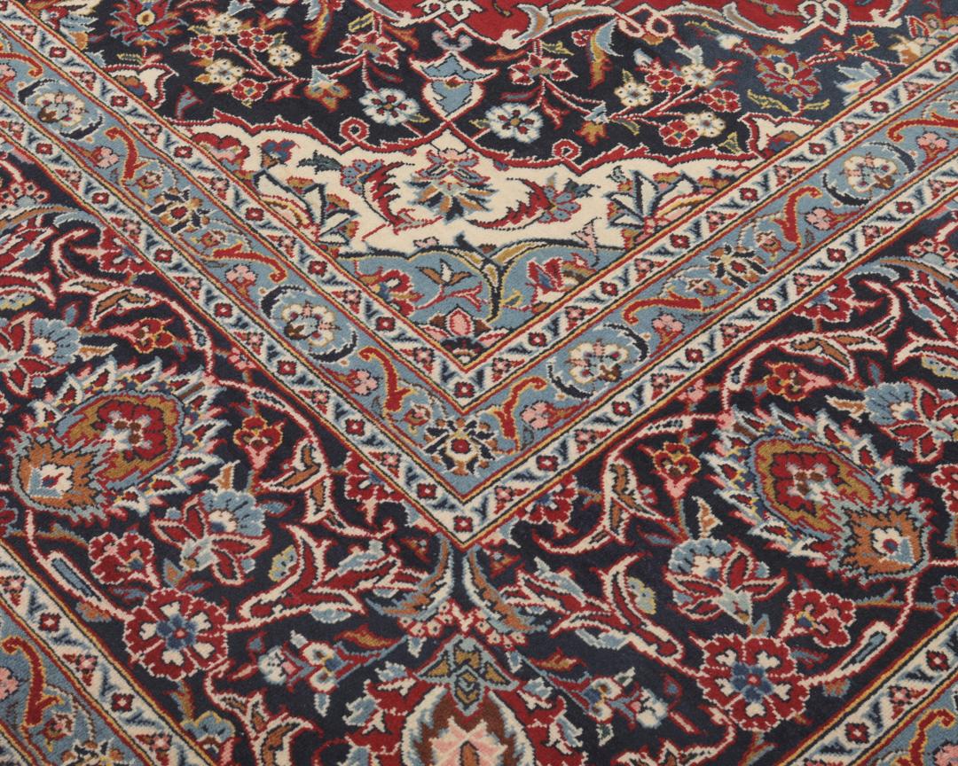 A hand-knotted Keshan rug from the Middle East with a red field and intricate floral patterns.