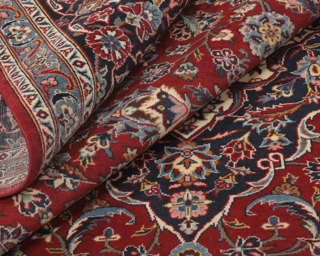 A hand-knotted Keshan rug from the Middle East with a red field and intricate floral patterns.