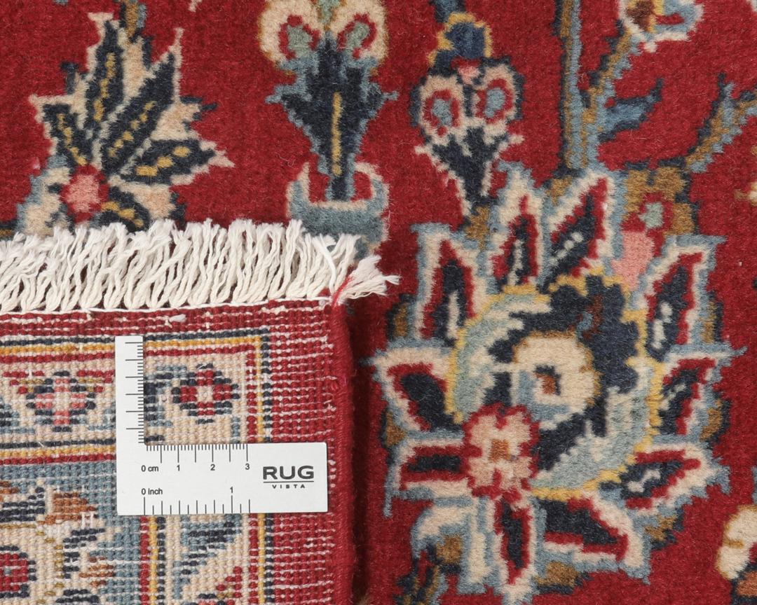A hand-knotted Keshan rug from the Middle East with a red field and intricate floral patterns.
