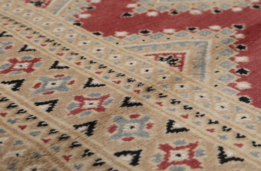 A hand-knotted red Pakistan Bokhara 2ply rug with geometric diamond motifs.