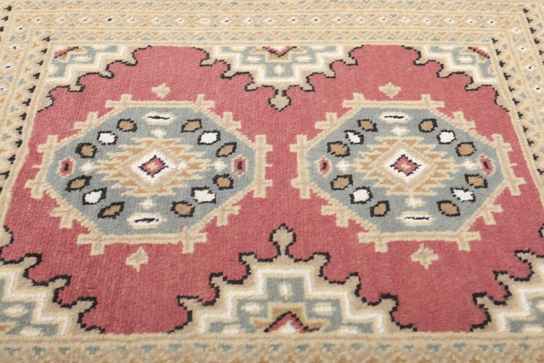 A hand-knotted Pakistan Bokhara rug in red and beige tones.