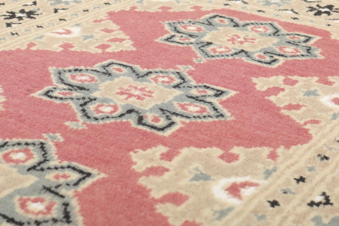 A hand-knotted Pakistan Bokhara rug in red and beige tones.