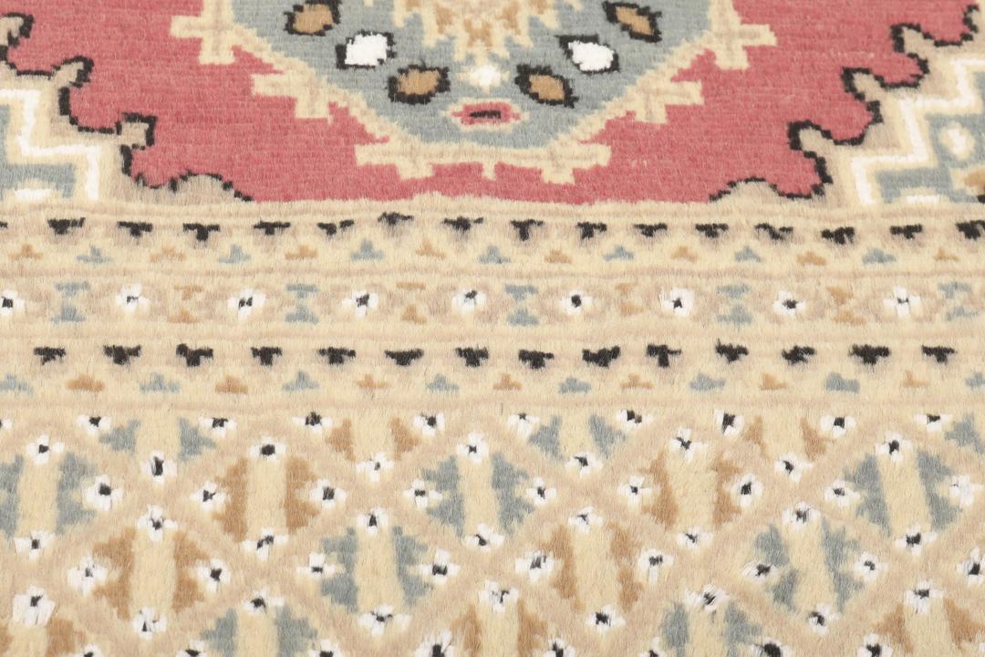 A hand-knotted Pakistan Bokhara rug in red and beige tones.