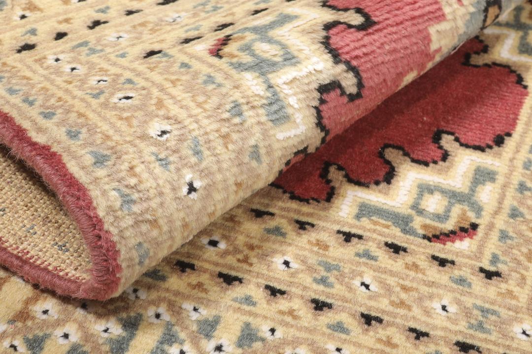 A hand-knotted Pakistan Bokhara rug in red and beige tones.