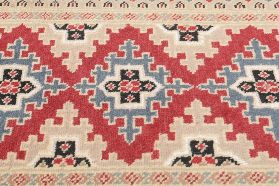 A hand-knotted Pakistan Bokhara 2ply rug featuring geometric patterns in red and beige tones.