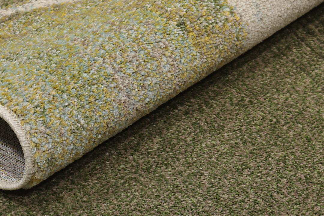 Et rektangulært tæppe med et abstrakt malerisk mønster i nuancer af creme, beige og grøn.