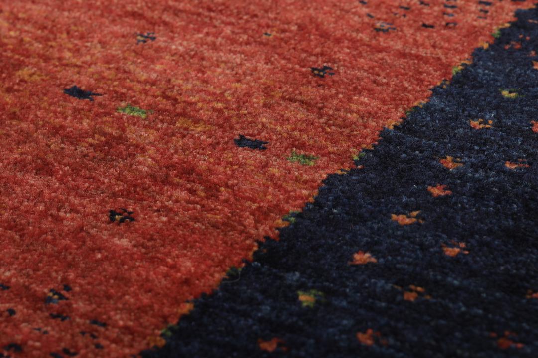 Hand-knotted Loribaft wool rug from the Middle East in red, orange, and blue.
