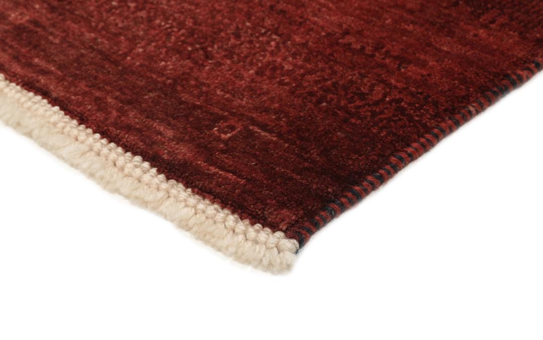 Een rechthoekig handgeknoopt Loribaft-tapijt uit het Midden-Oosten in een dieprode kleur.