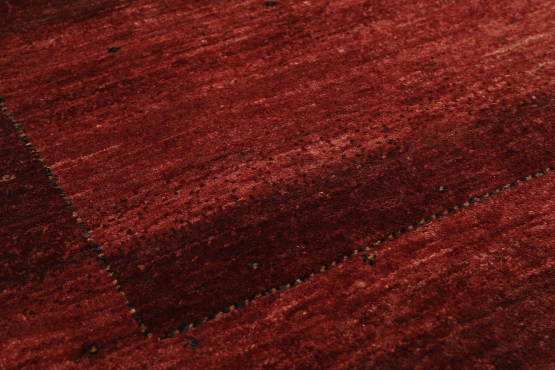Een handgeknoopt Loribaft tapijt uit het Midden-Oosten in diepe donkerrode tinten.
