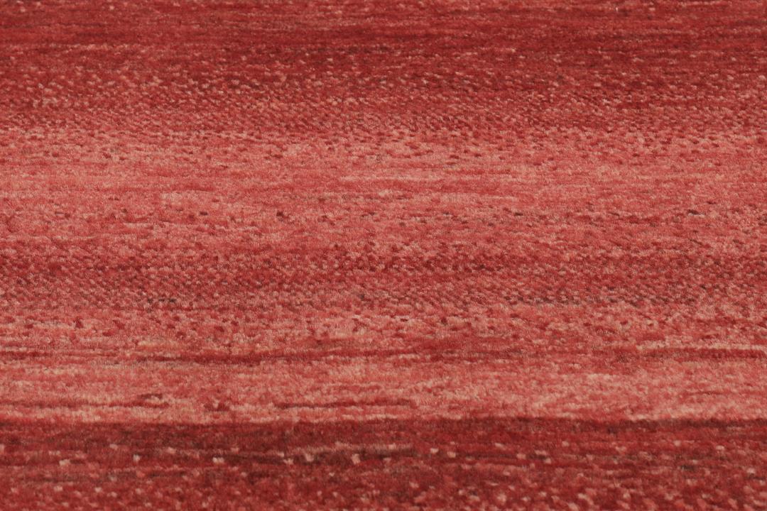 Een met de hand geknoopt rood Loribaft-tapijt uit het Midden-Oosten met een diepe, rijke kleur.