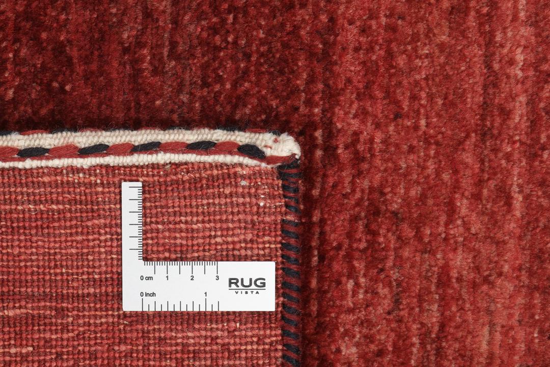 Een met de hand geknoopt rood Loribaft-tapijt uit het Midden-Oosten met een diepe, rijke kleur.