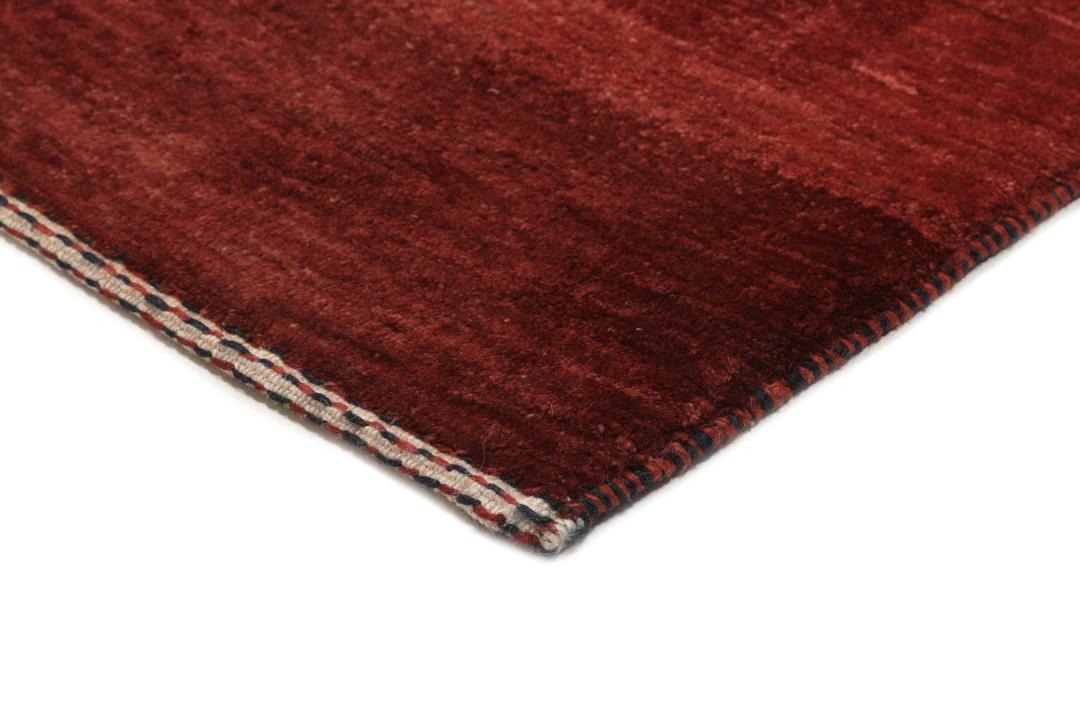 Een handgeknoopt Loribaft Fine tapijt uit het Midden-Oosten in een diepe donkerrode tint.