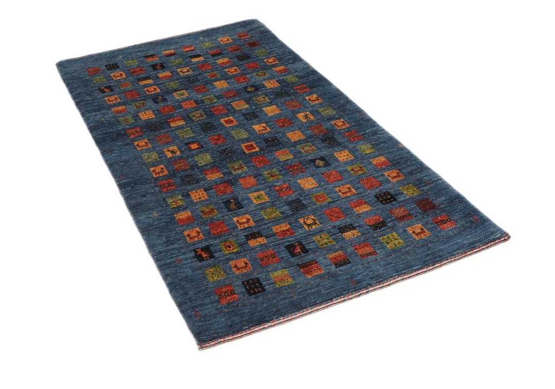 Een handgeknoopt Loribaft-kleed uit het Midden-Oosten met een blauw veld en kleurrijke vierkante motieven.