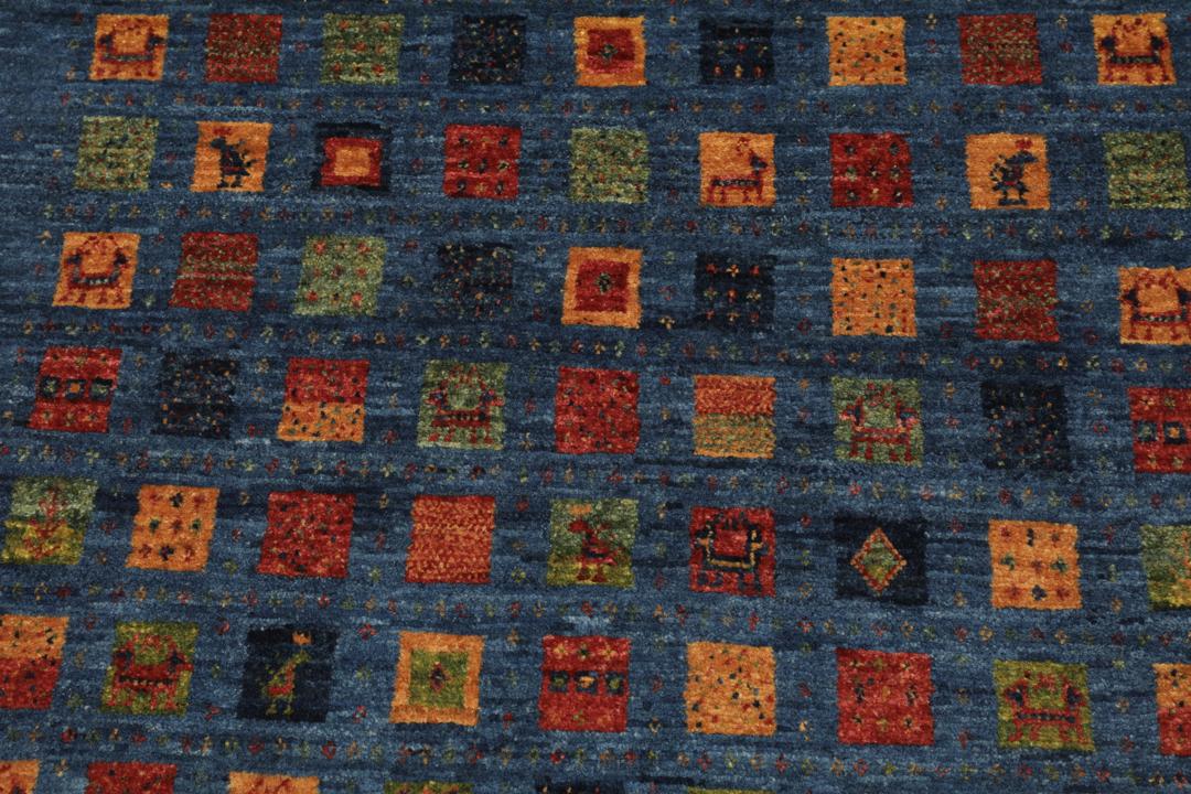 Een handgeknoopt Loribaft-kleed uit het Midden-Oosten met een blauw veld en kleurrijke vierkante motieven.