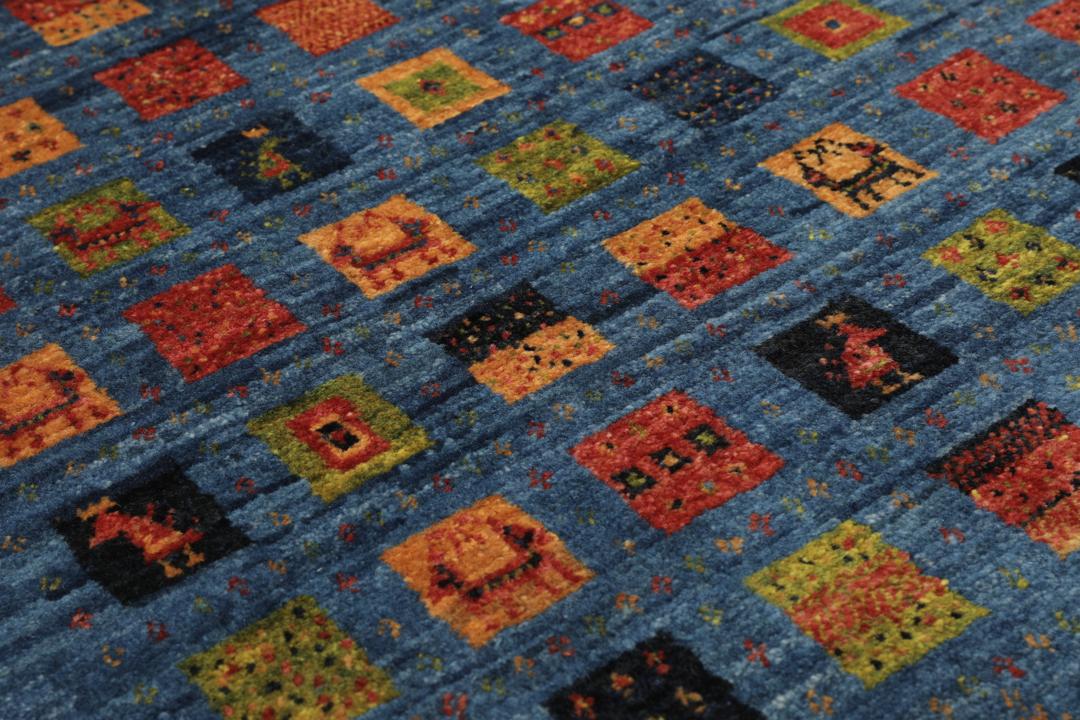 Een handgeknoopt Loribaft-kleed uit het Midden-Oosten met een blauw veld en kleurrijke vierkante motieven.