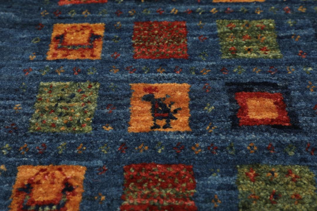 Een handgeknoopt Loribaft-kleed uit het Midden-Oosten met een blauw veld en kleurrijke vierkante motieven.