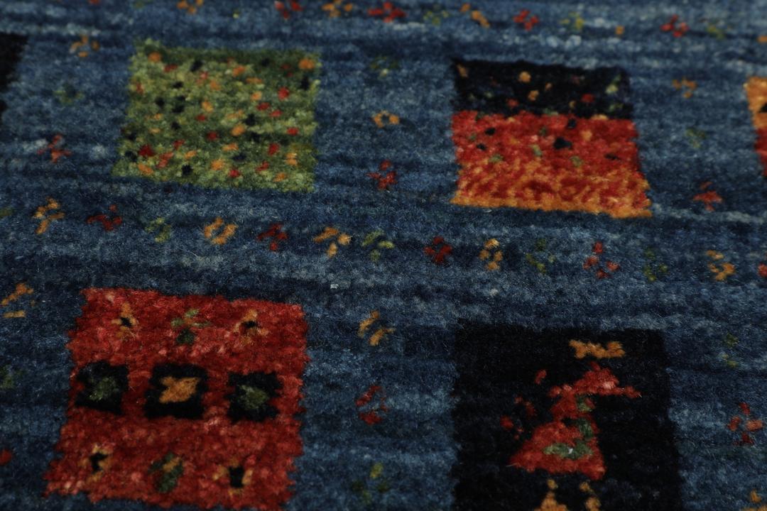 Een handgeknoopt Loribaft-kleed uit het Midden-Oosten met een blauw veld en kleurrijke vierkante motieven.