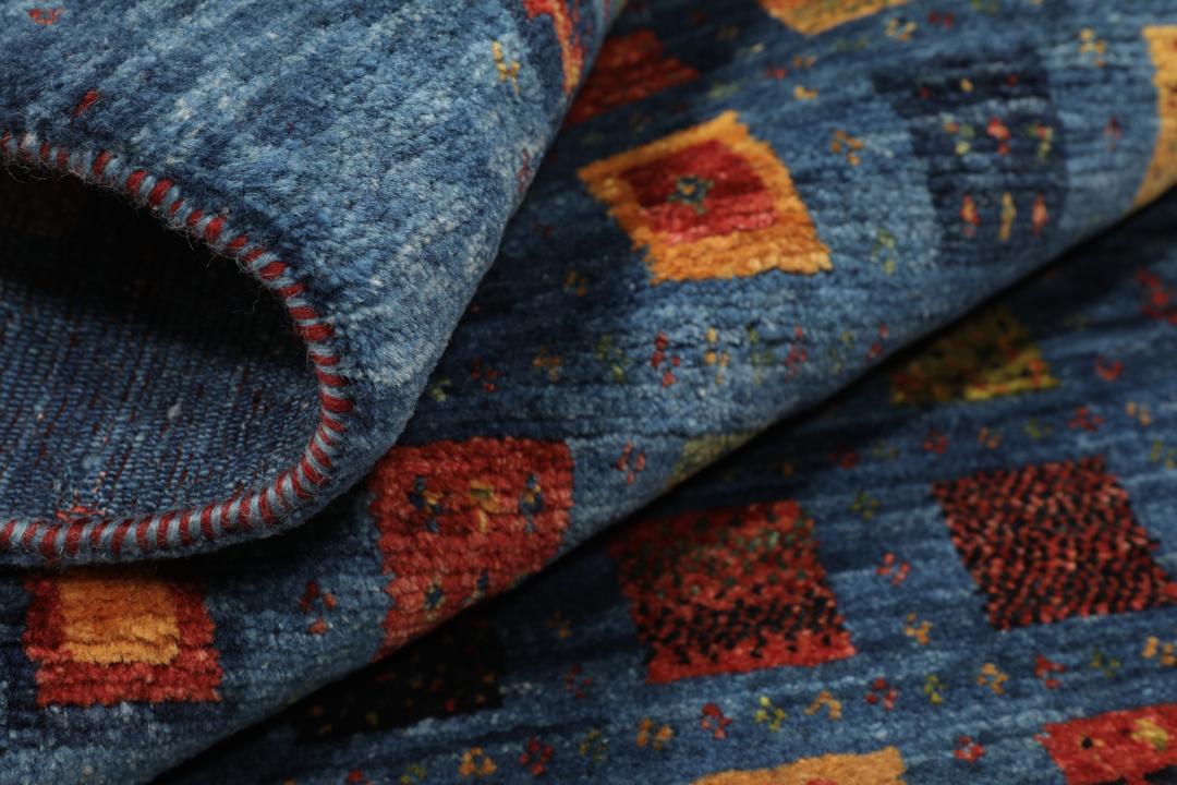 Een handgeknoopt Loribaft-kleed uit het Midden-Oosten met een blauw veld en kleurrijke vierkante motieven.