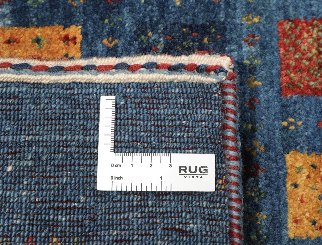 Een handgeknoopt Loribaft-kleed uit het Midden-Oosten met een blauw veld en kleurrijke vierkante motieven.