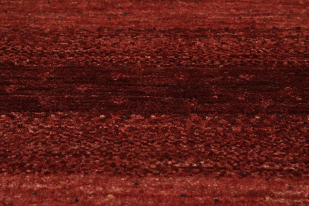 A hand-knotted Loribaft Fine rug from the Middle East in deep red tones.